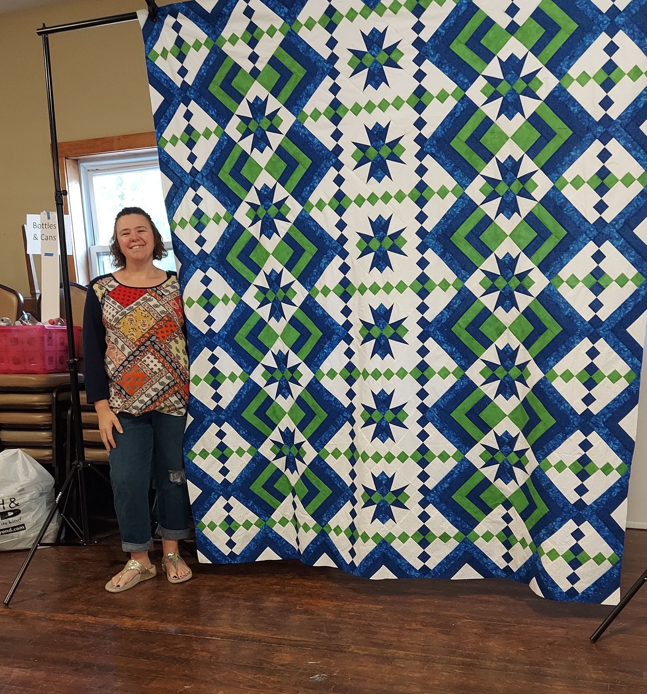 Aimee Yorsaner standing next to large quilt