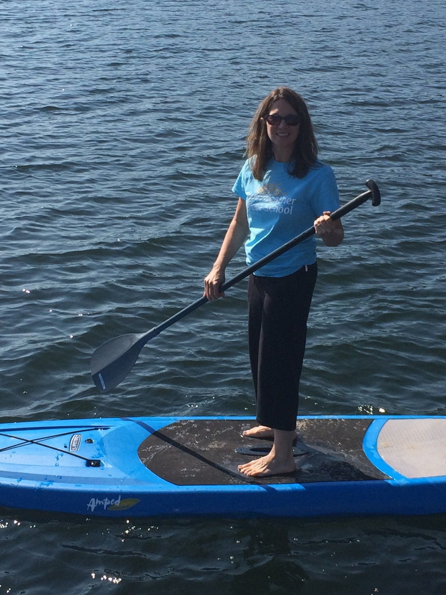 Robin Khadduri stand up paddleboarding in a lake. 