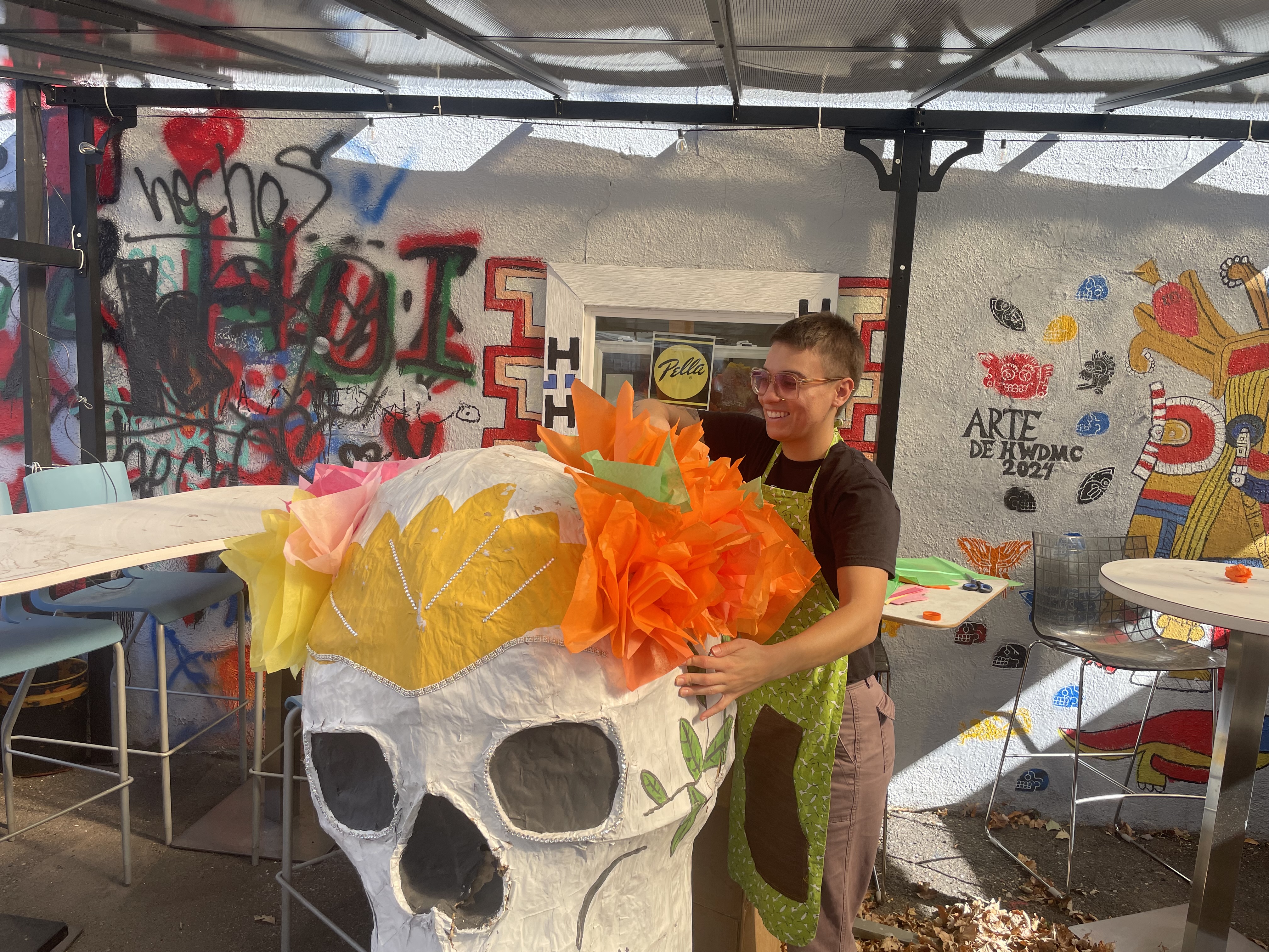 Shayla sculpting a big paper skull in a colorful studio. 