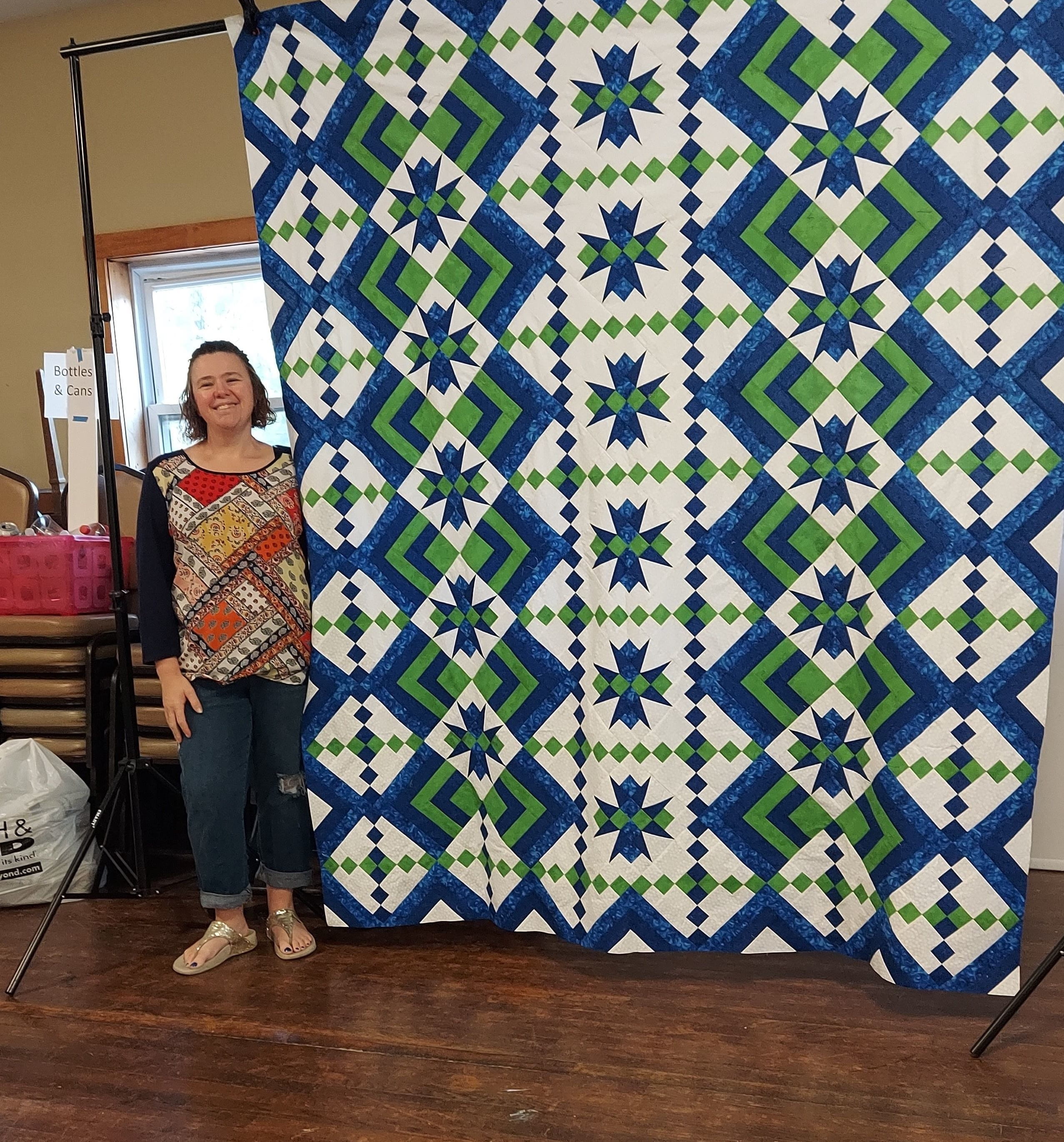 Aimee Yorsaner standing next to large quilt